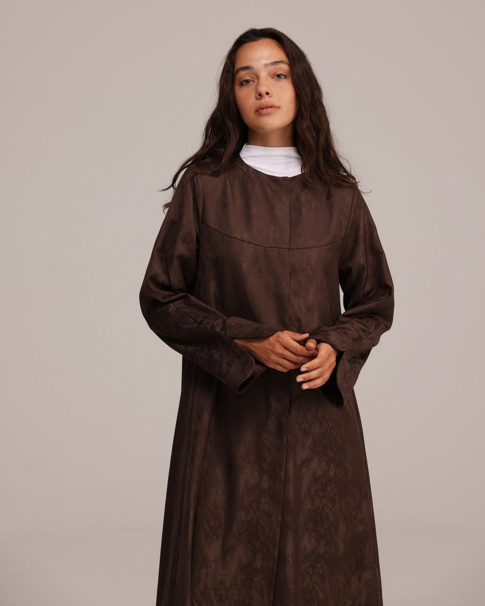 Woman wearing a brown dress against a plain background