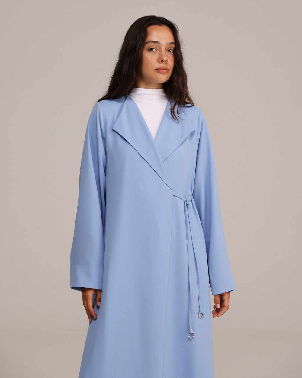 Woman wearing a light blue coat against a plain background