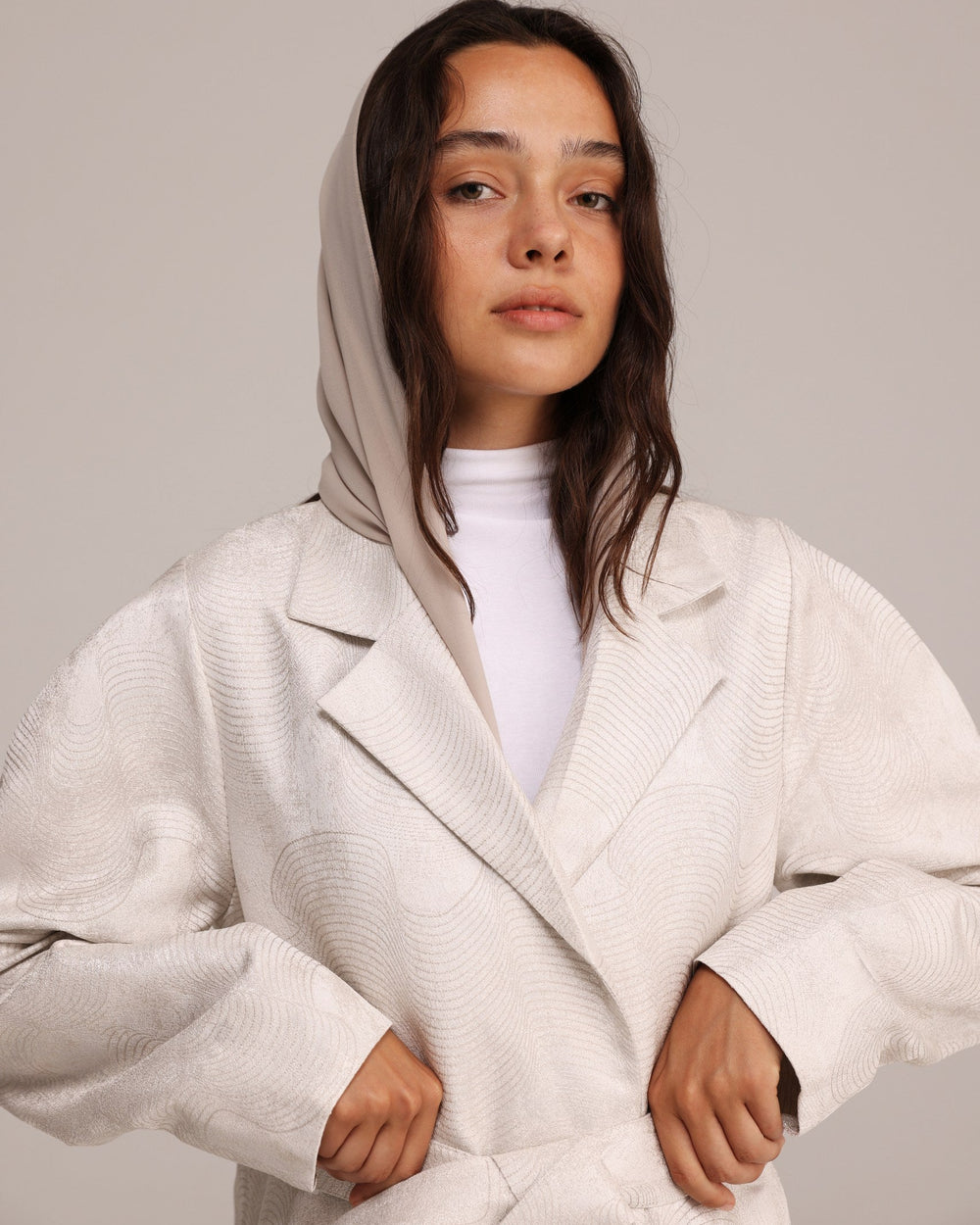 Woman wearing a white coat against a plain background