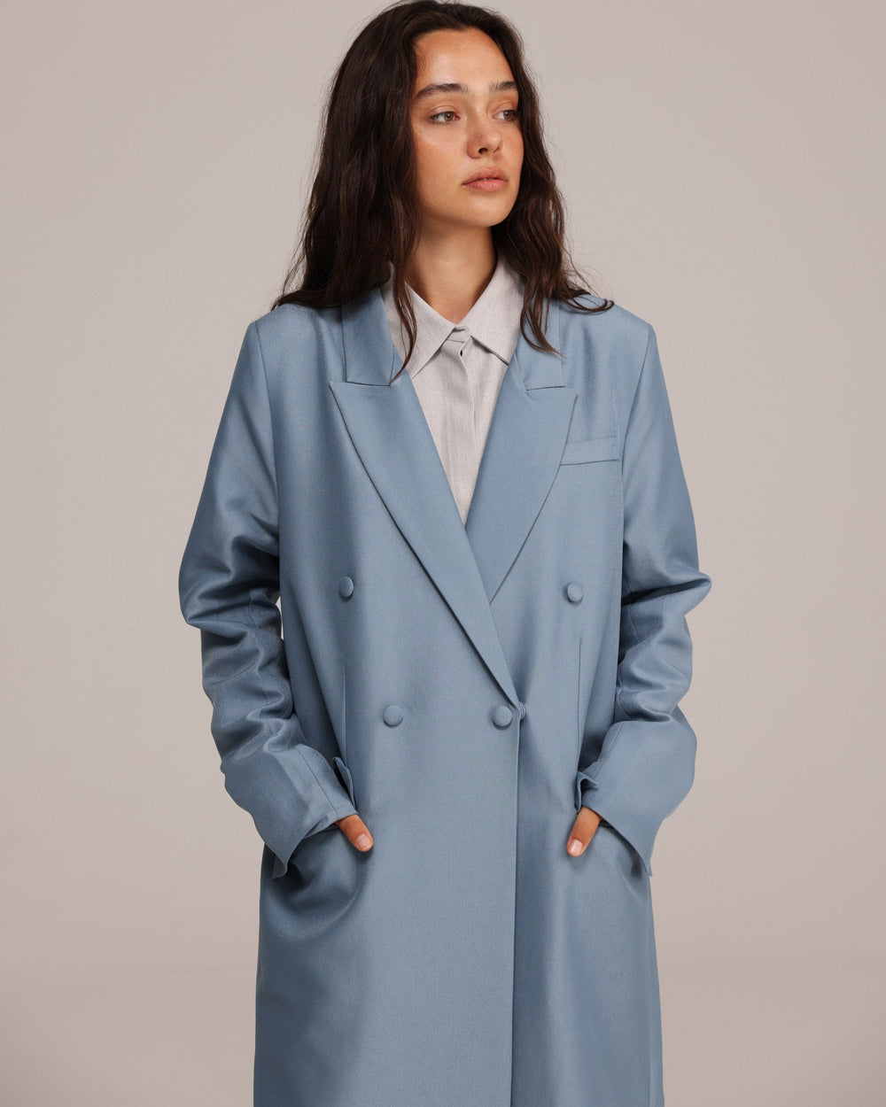 Woman wearing a light blue coat against a plain background