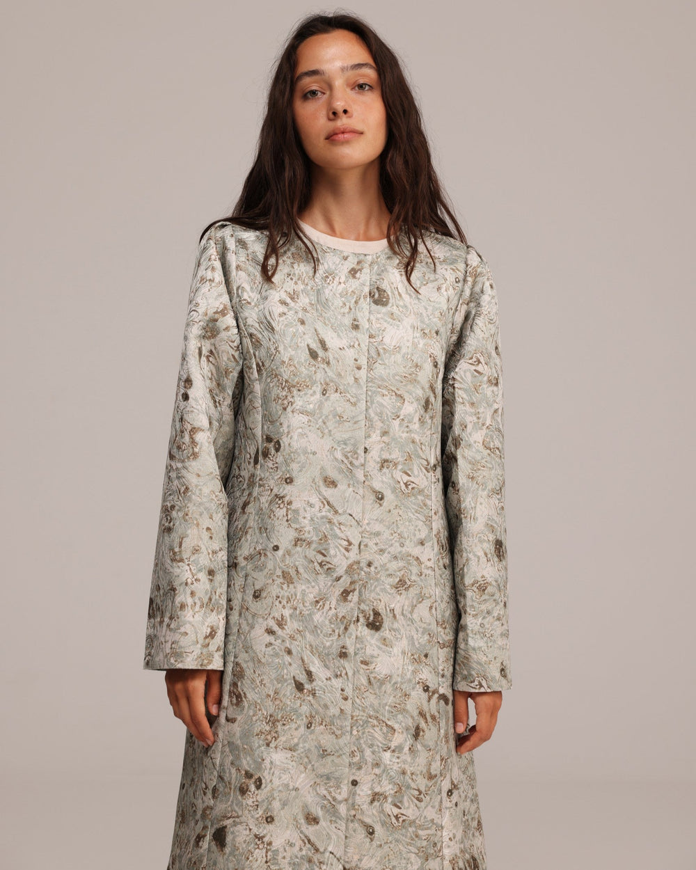 Woman wearing a long floral dress against a plain background