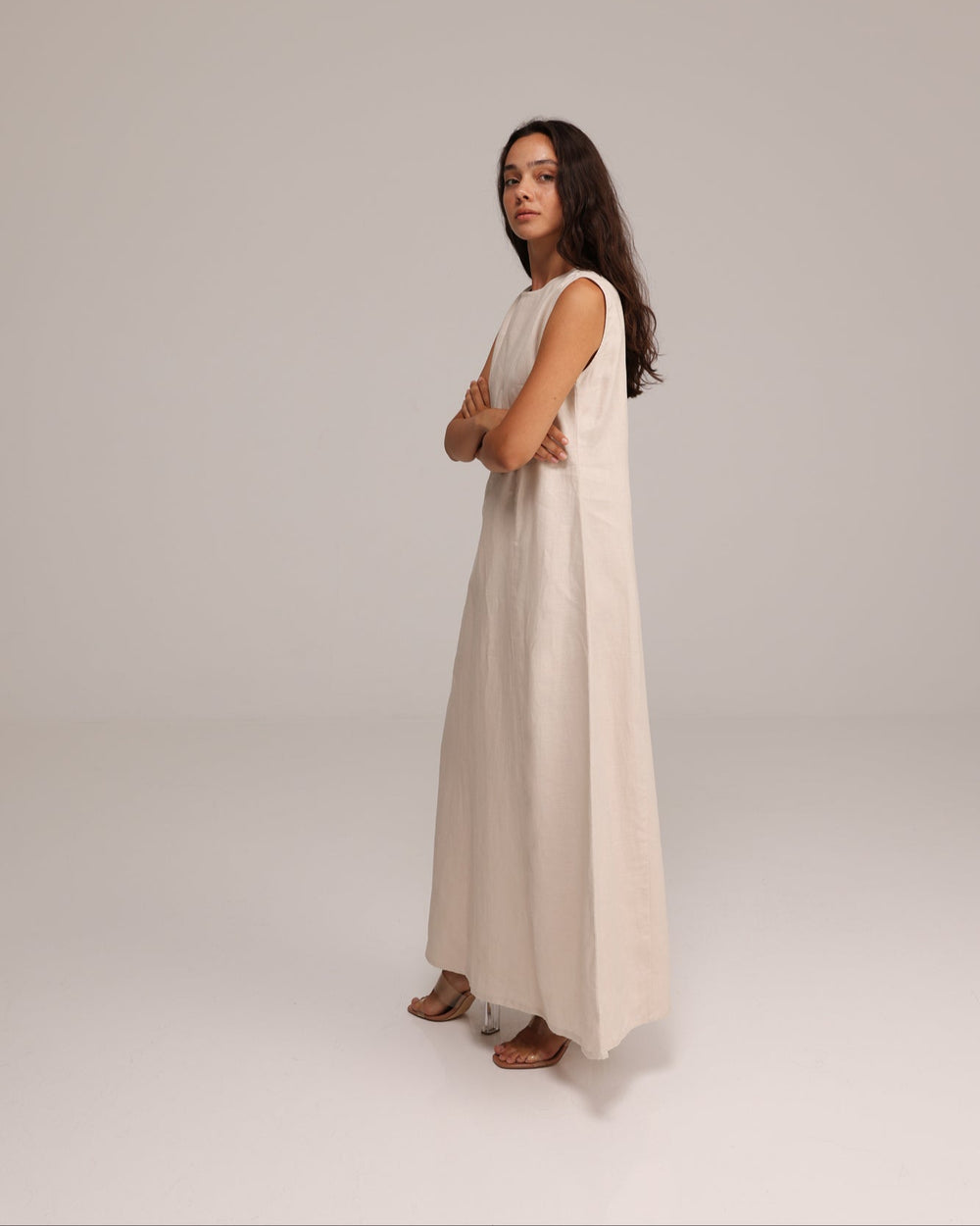 Woman wearing a long, light-colored dress against a plain background