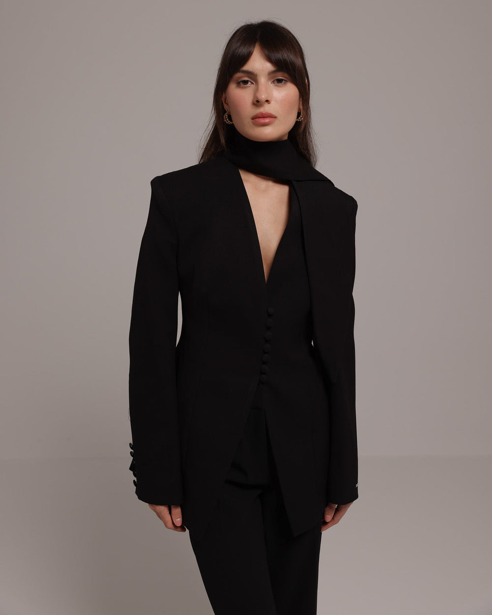 Woman wearing a black BLAZER against a plain background